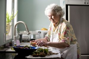 portrait of elderly woman in kitchen pictured while preparing a meal 725x483 1