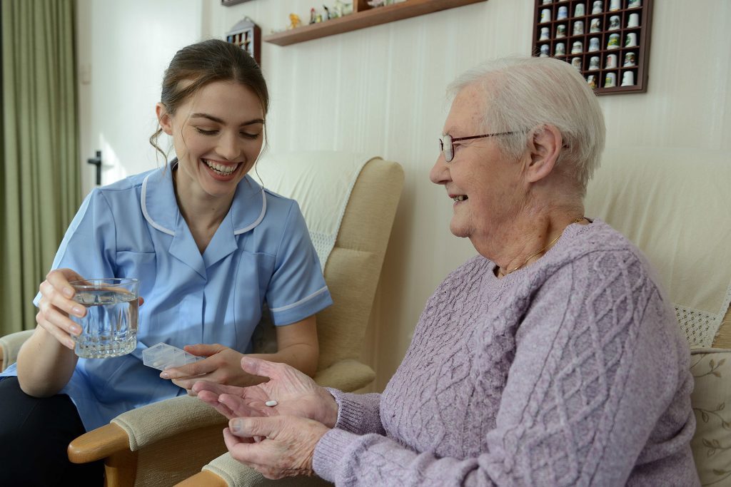 Carer giving medication to elderly lady 